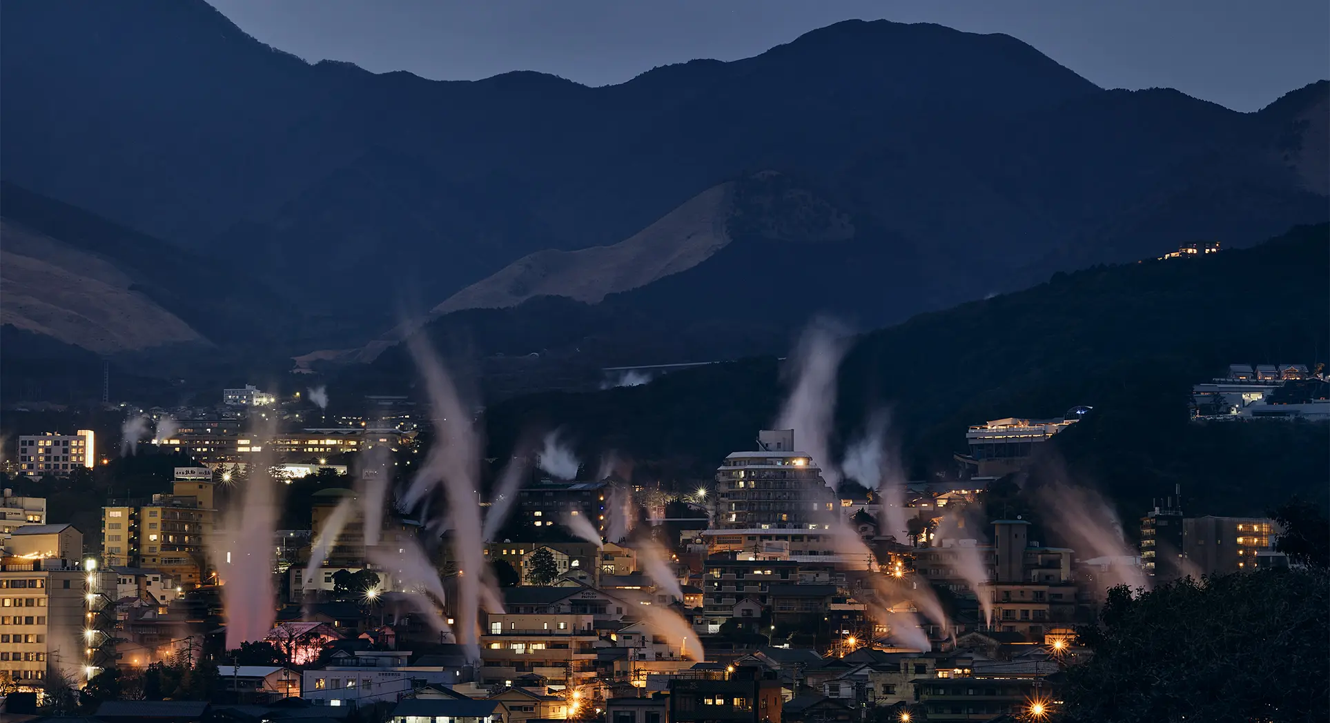 View of the city of Beppu at night with rising steam – a highlight for travellers to Japan