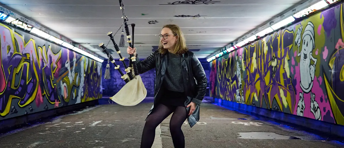 The young Scottish piper Emma Hill messing around with her pipes during a photo shoot in a subway station with graffiti-covered walls