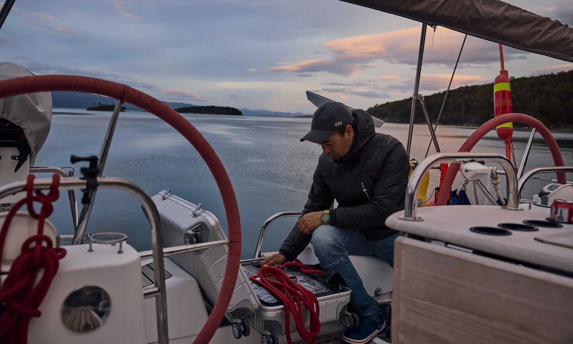 A man places a rope in a Lufthansa Aluminium Collection suitcase behind the helm of a sailing ship