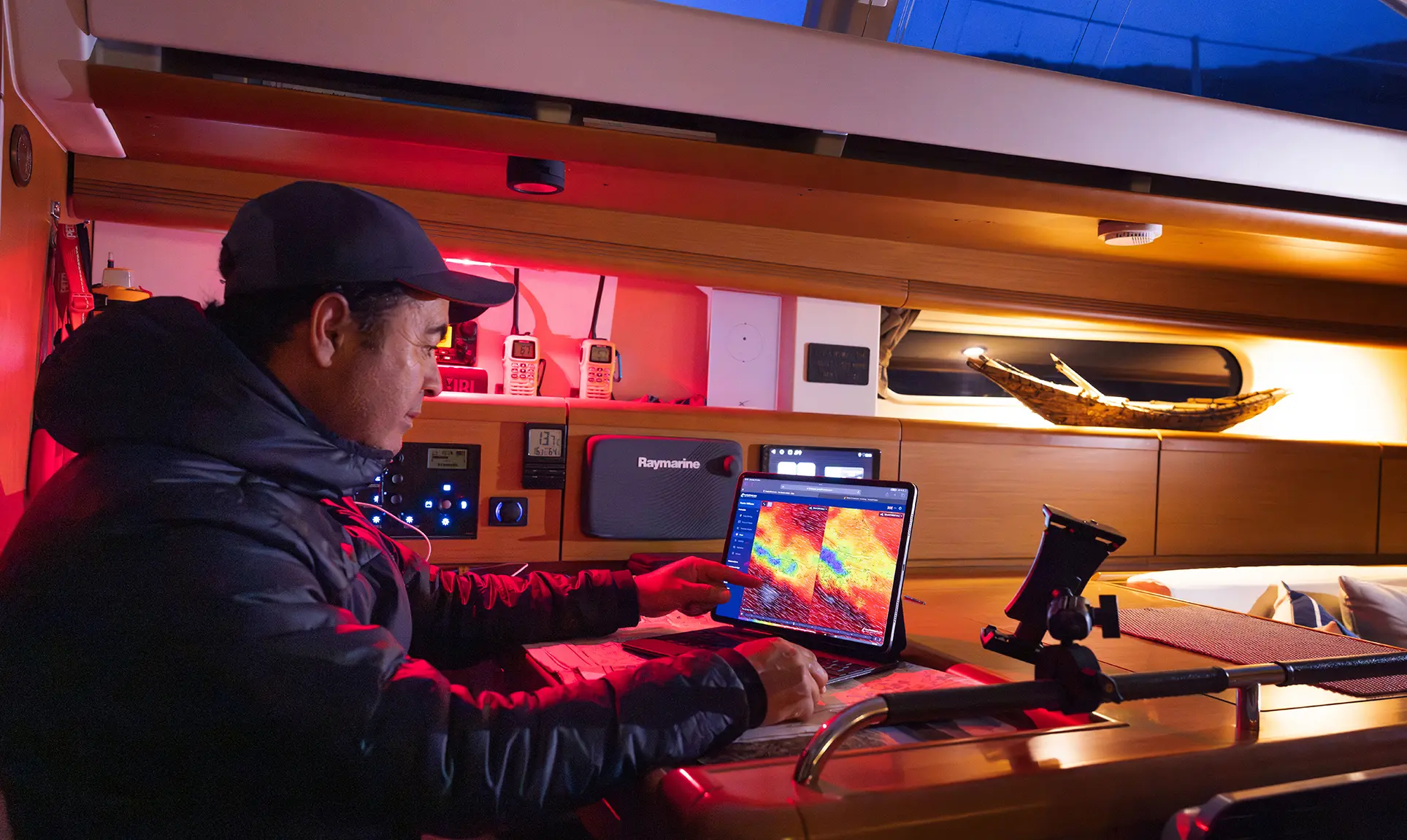 A man studies weather charts on a display in a cabin at dusk