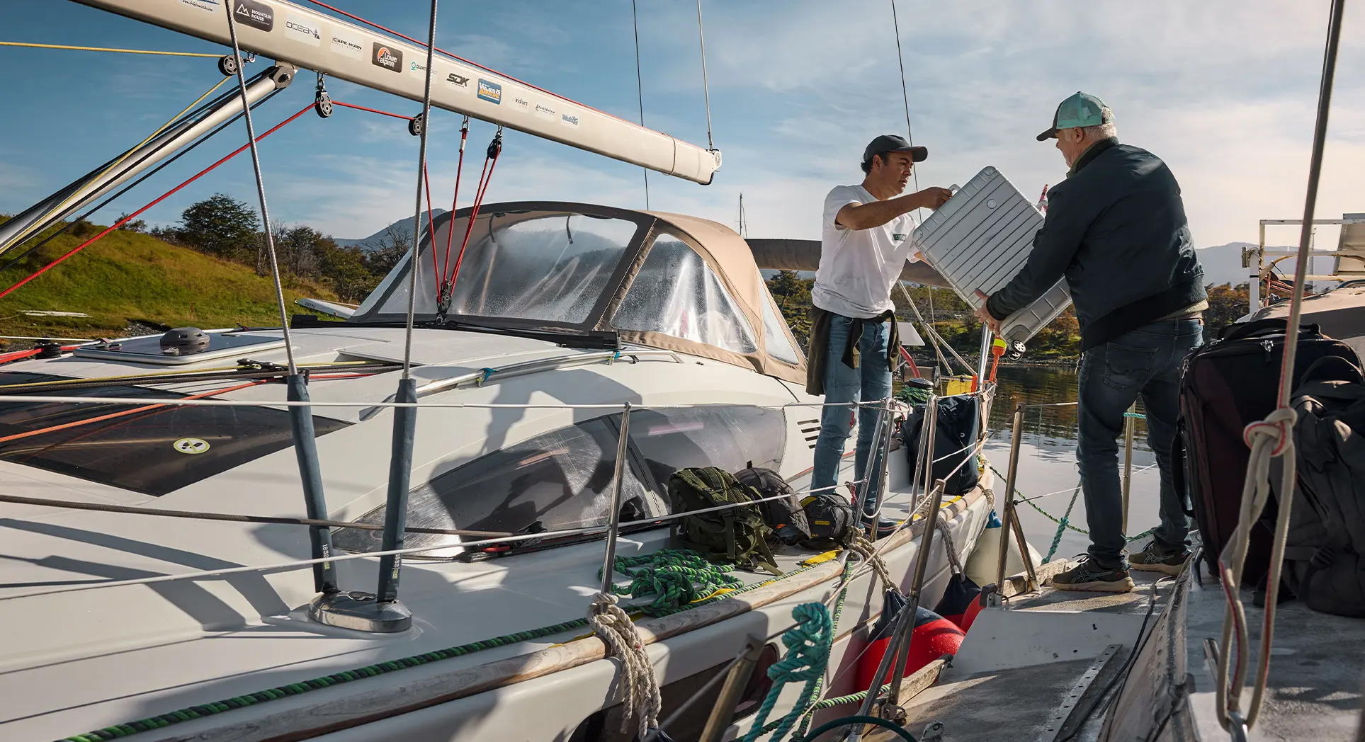 Two men lift a Lufthansa Aluminium Collection suitcase on board a sailing yacht