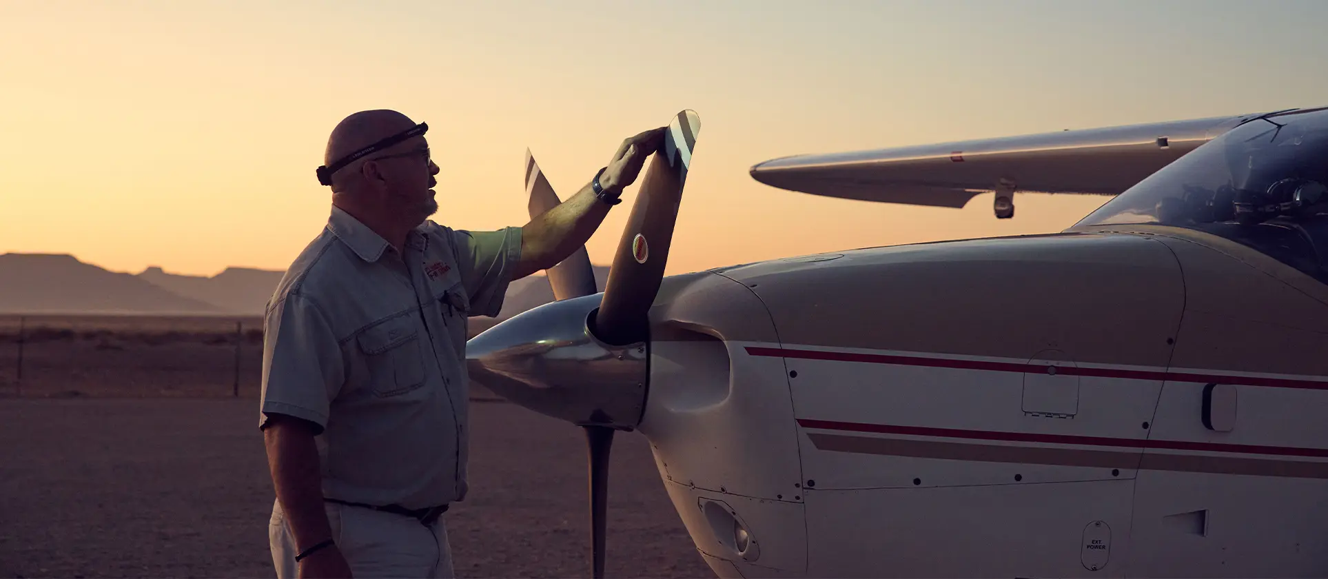 Pilot turns propeller of Cessna at dawn
