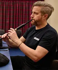 The Scottish professional piper Finlay MacDonald blowing into a bagpipe