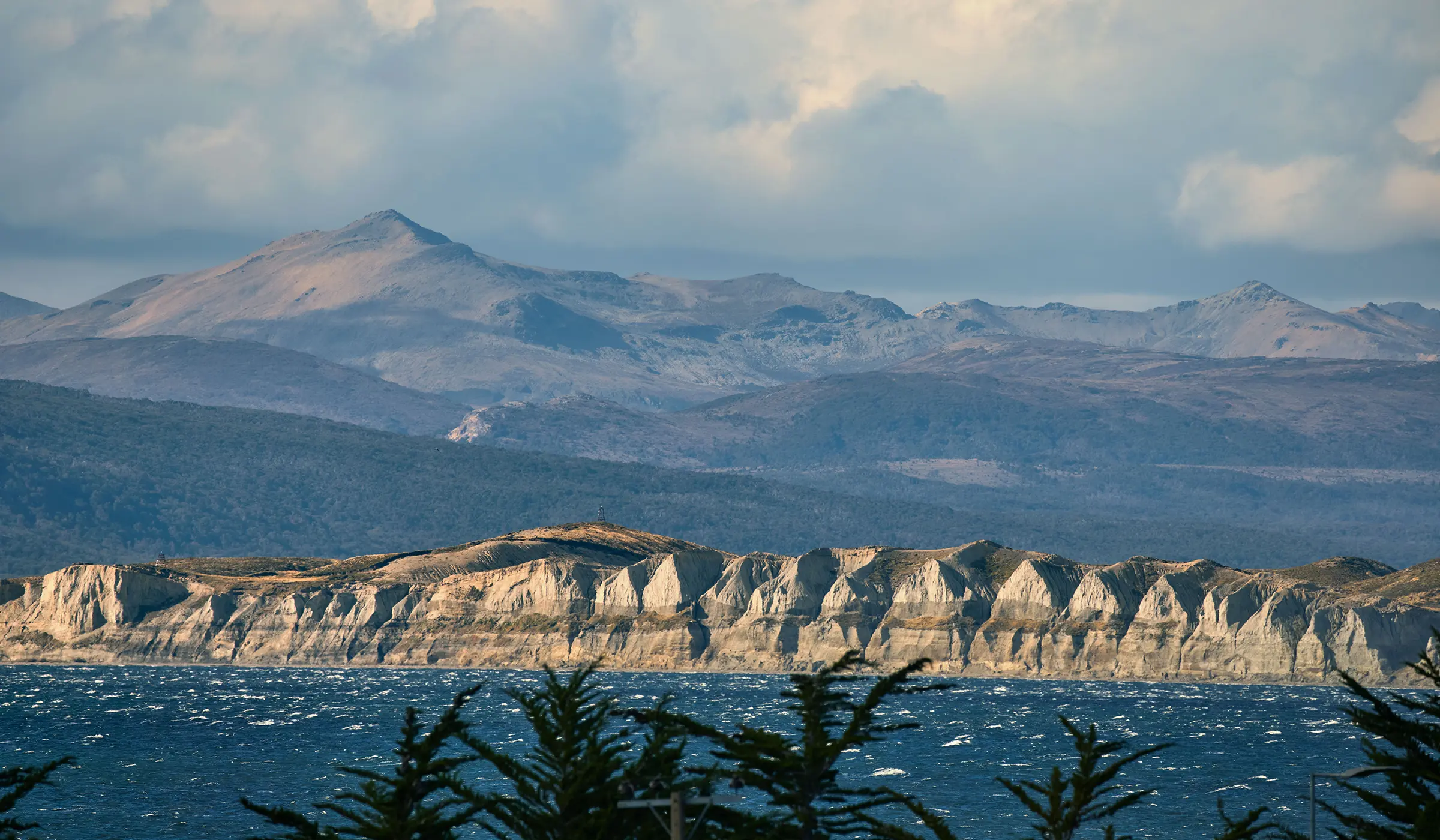 Steep white sea cliffs with wooded hills and mountains in the background