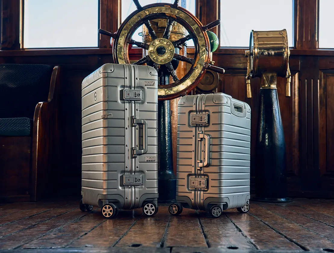 Suitcase in front of the steering wheel of a sailing ship