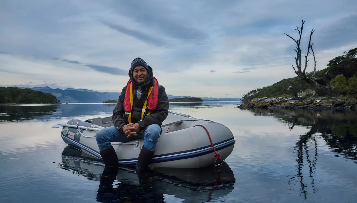 A man sits in an inflatable boat on calm water